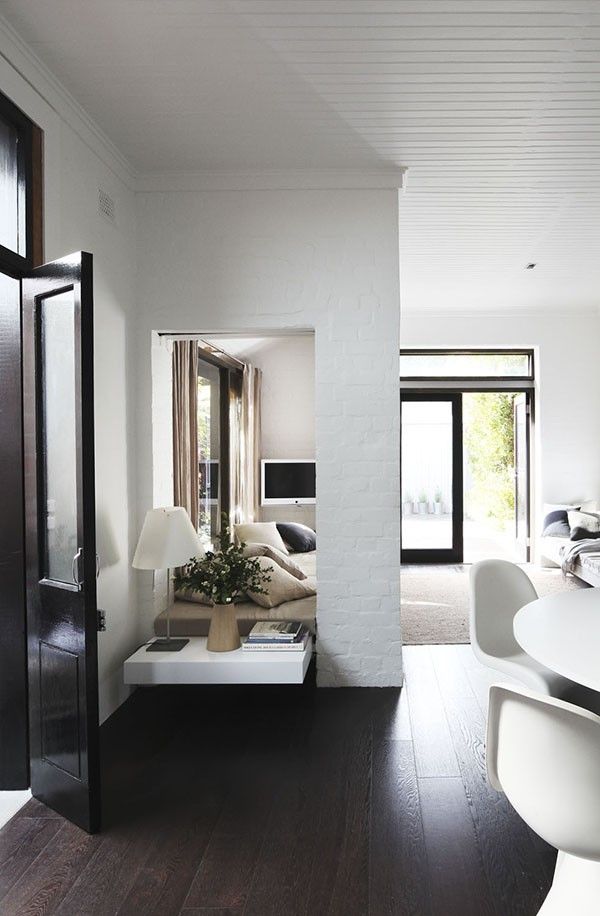 an open living room and dining area with wood floors, white walls and black doors