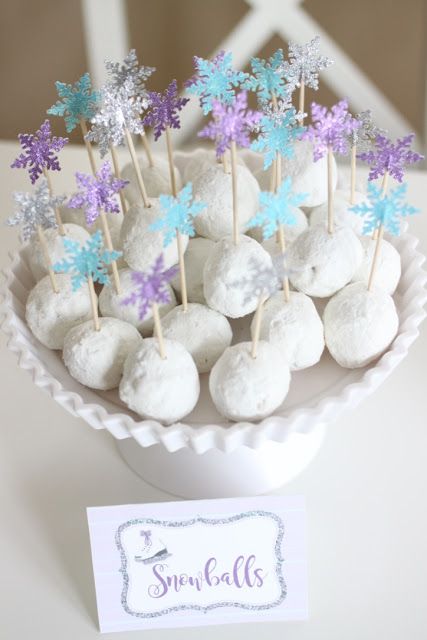 there are some snowballs on sticks in the cupcakes holder with purple and blue frosting