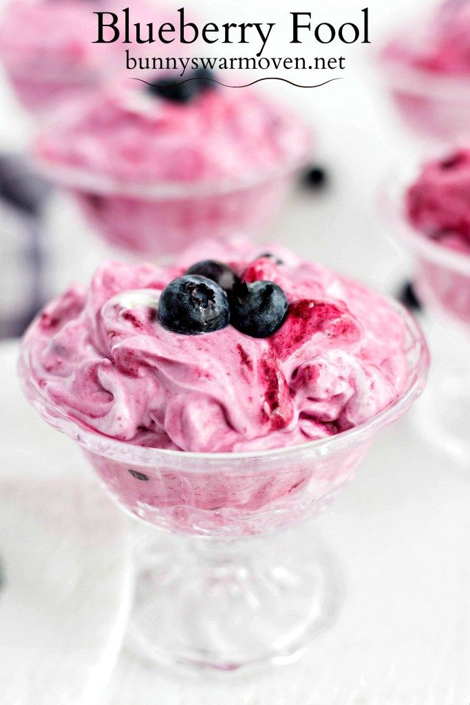 blueberries and yogurt in small glass bowls on a white table with blackberries