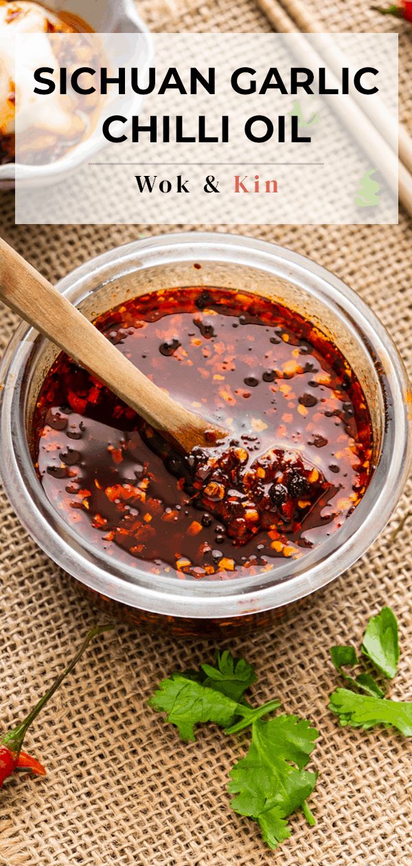 a bowl filled with chili sauce next to a wooden spoon on top of a table