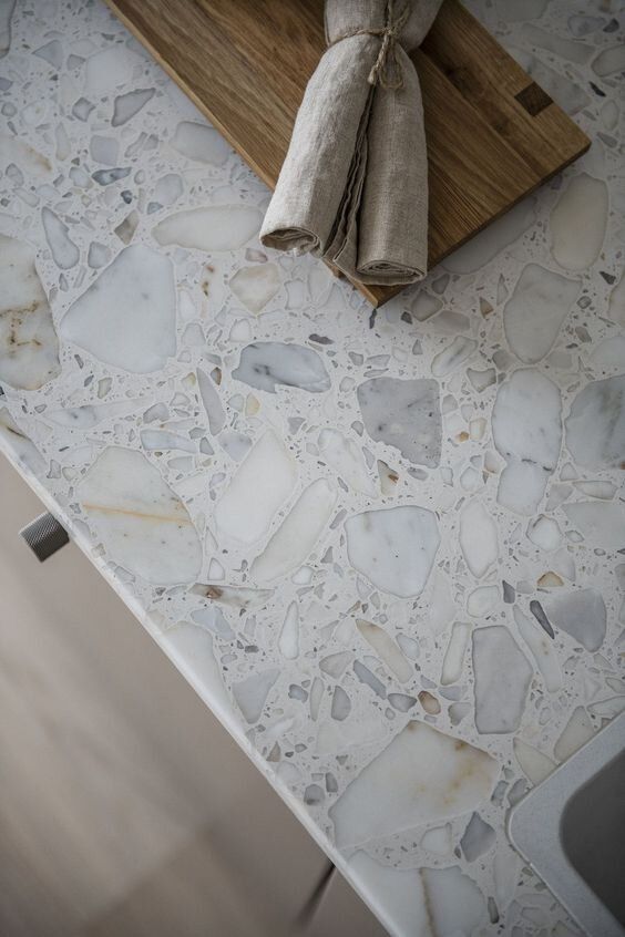 a wooden cutting board sitting on top of a counter next to a marble tiled floor