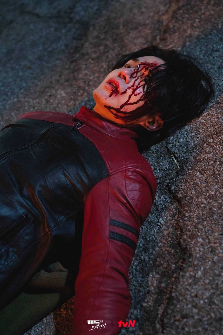 a man with blood all over his face laying on the ground next to a wall