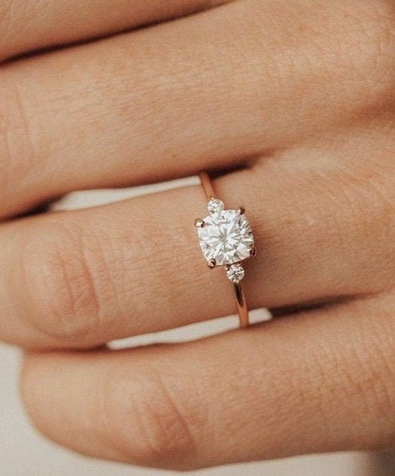 a woman's hand with a diamond ring on top of her finger and an engagement band