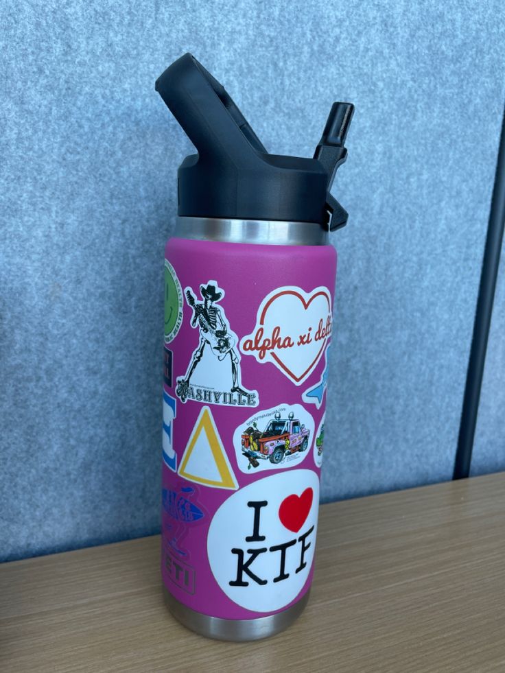 a pink insulated water bottle with stickers on it