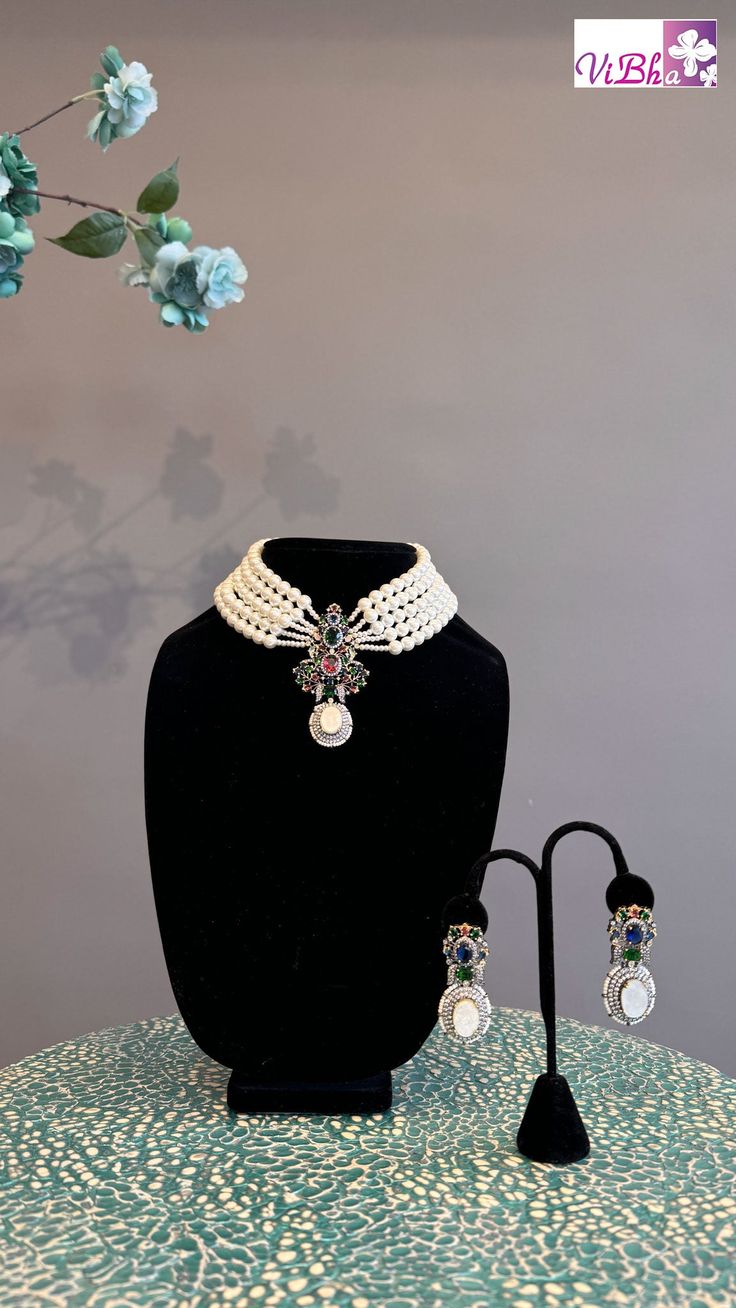 Indulge in luxury with our elegant Pearl 5-Line Choker set. Adorned with ruby emeralds, sapphires, and ADs, this pendant and earring set adds a sophisticated touch to any outfit. Its versatility allows it to be worn with various ensembles, exuding a regal charm. Elevate your style with this exclusive set. Elegant Multi-stone Emerald Necklace For Formal Occasions, Elegant Multi-stone Emerald Jewelry, Elegant Multi-stone Jewelry Sets For Gifts, Elegant Multi-stone Jewelry Sets As A Gift, Elegant Multicolor Gemstone Emerald Necklace, Formal Multi-stone Emerald Jewelry, Elegant Multicolor Gemstone Necklace, Elegant Jeweled Emerald Jewelry, Elegant Multicolor Multi-stone Jewelry Sets