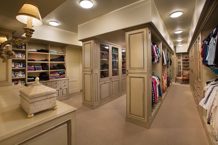 a walk in closet with lots of clothes on shelves and lights hanging from the ceiling