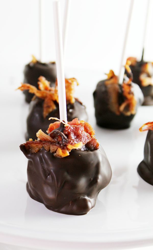 chocolate covered candies with bacon on top and white stick sticking out of the middle