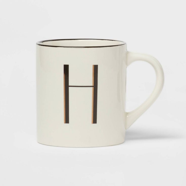 a white and black coffee mug with the letter h on it's front side