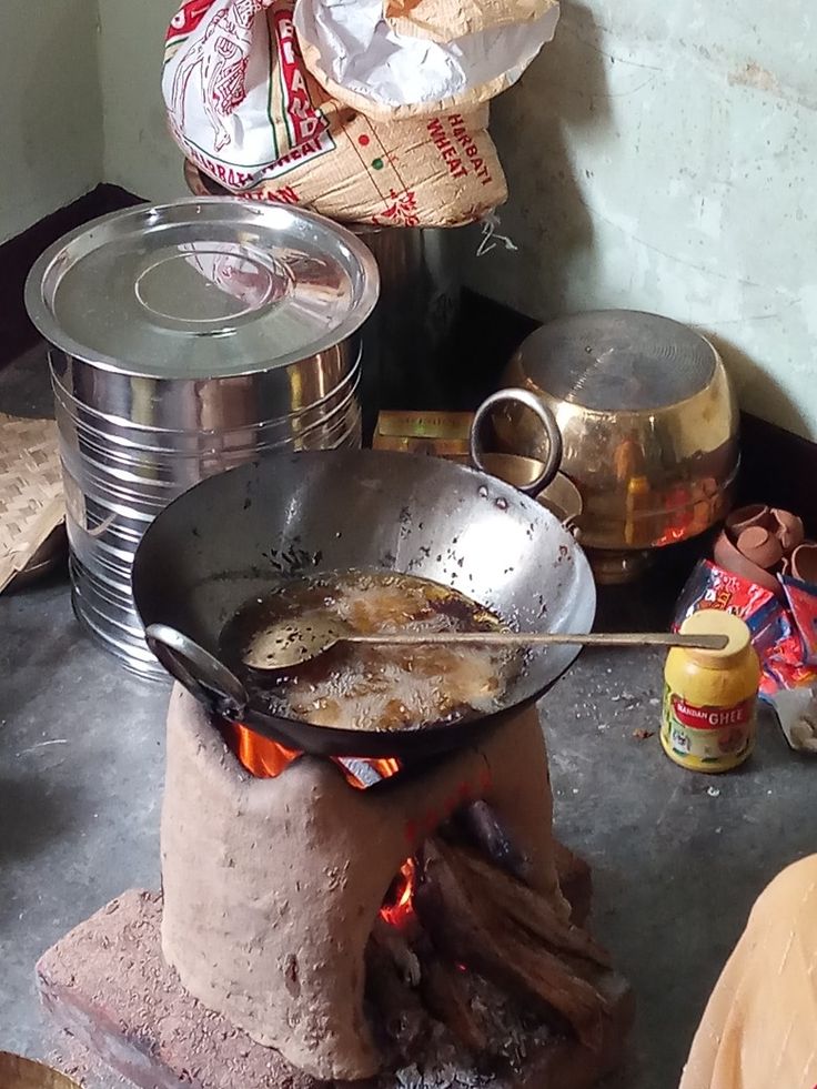 an outdoor stove with pots and pans cooking food on it's burners