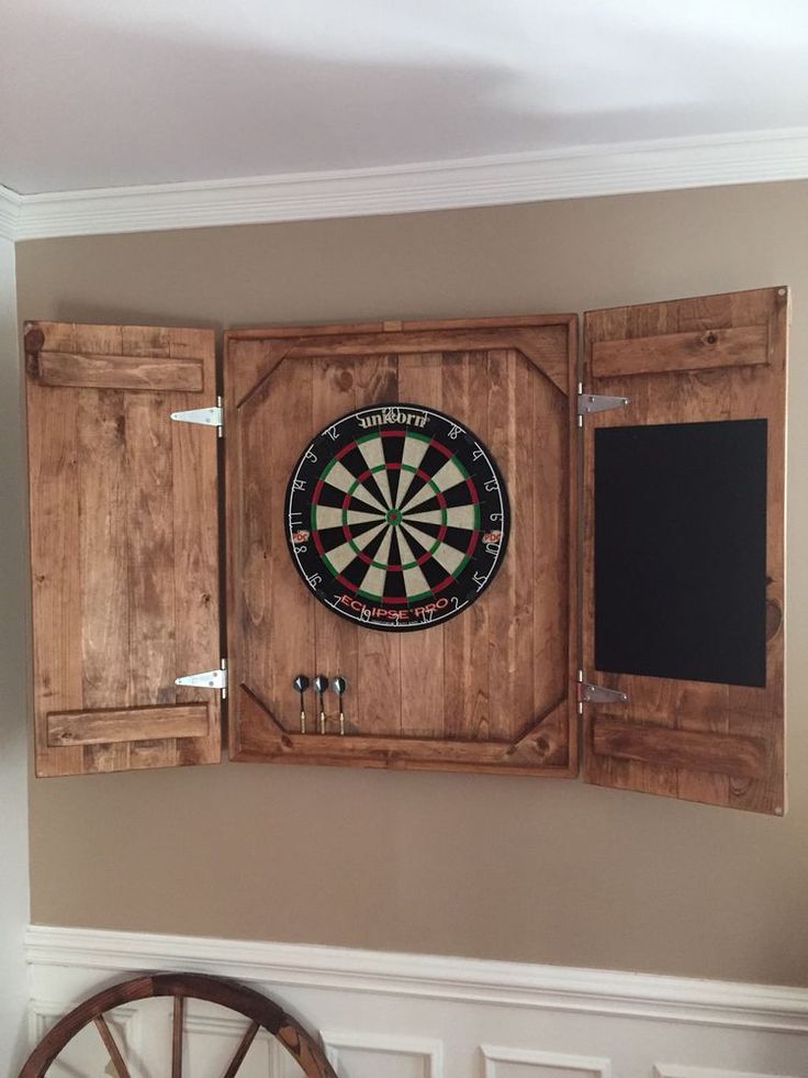 a dart board mounted to the side of a wooden cabinet with two darts in it