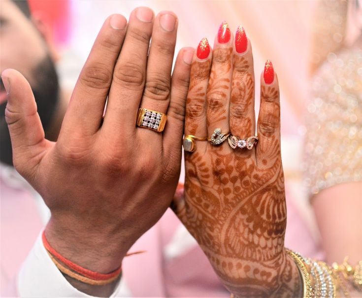 the bride and groom are holding their hands up to each other with rings on them