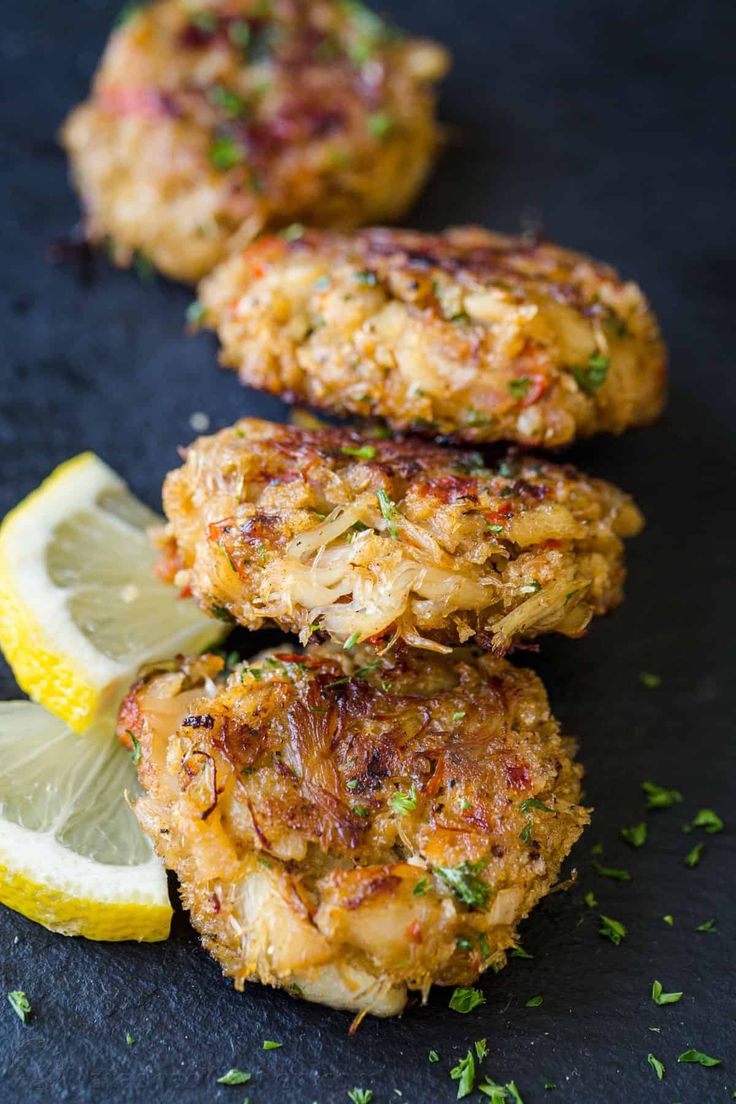 three crab cakes with lemon wedges and parsley on the side, ready to be eaten