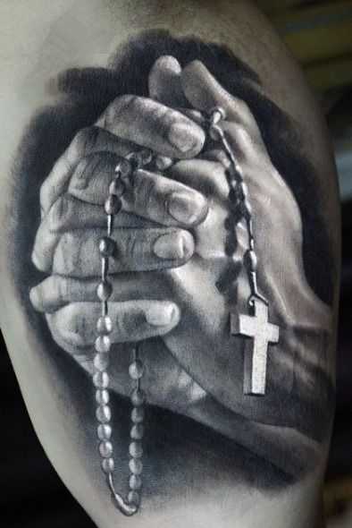 a black and white photo of two hands holding a rosary with the cross on it