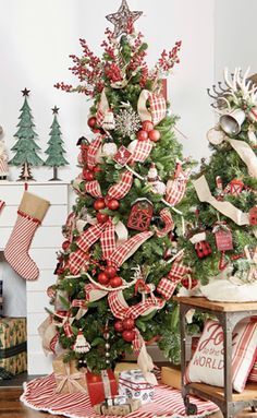 a christmas tree decorated with red and white ribbon, ornaments and stockings in a living room