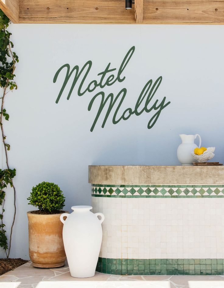 there is a sign that says motel moly on the wall next to two potted plants