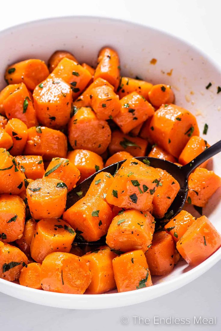 a white bowl filled with cooked carrots and herbs