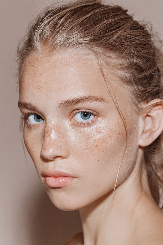 a woman with freckles on her face is looking at the camera while she has blue eyes