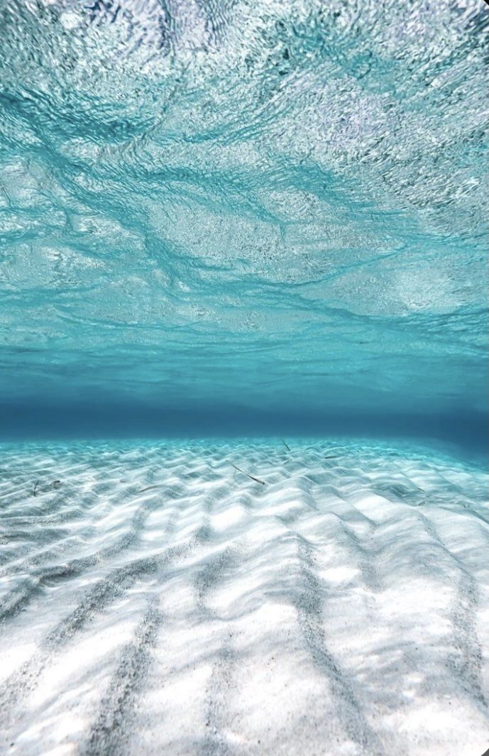 an underwater view of the ocean with sand and water ripples on the bottom, as seen from below