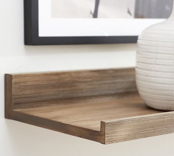 a white vase sitting on top of a wooden shelf next to a framed photo in a room