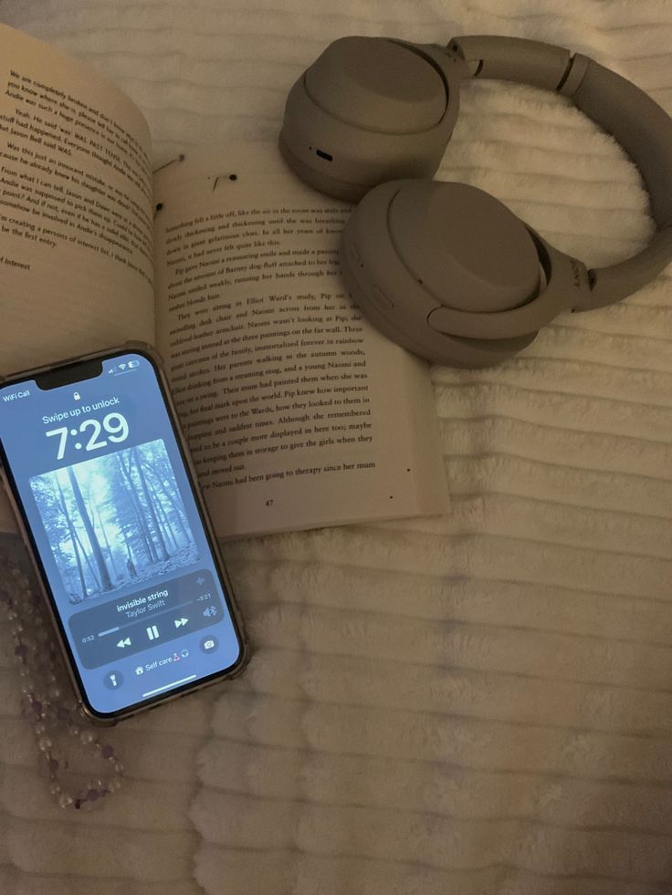 an open book and headphones on top of a bed