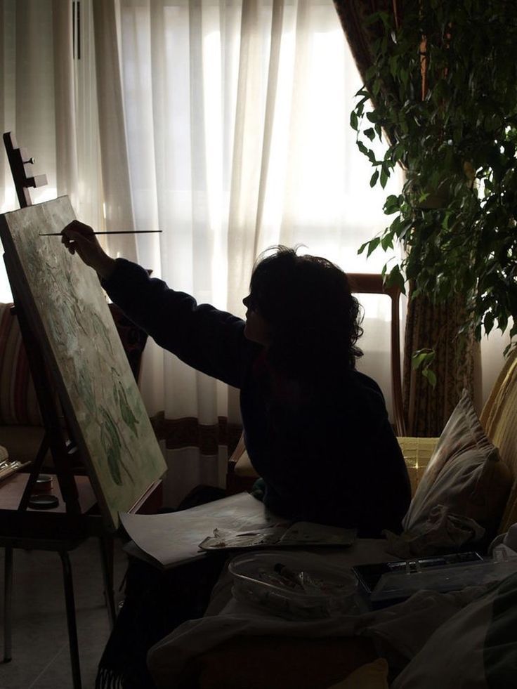 a woman is painting on an easel in her living room