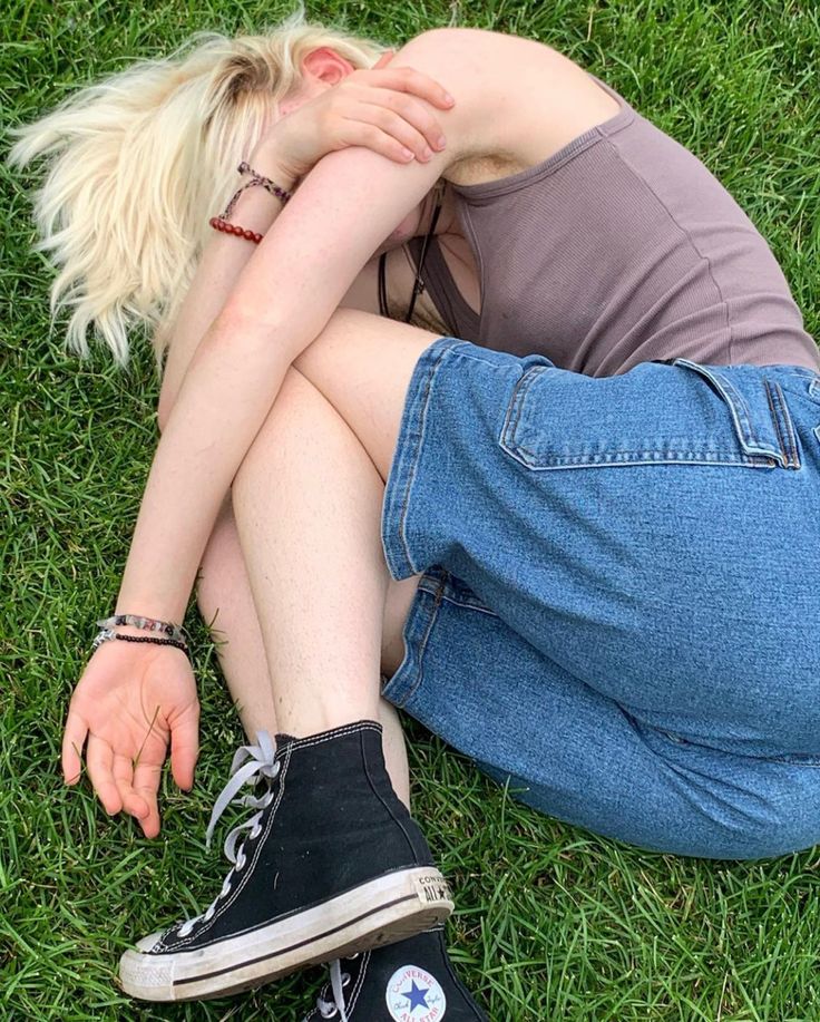 a woman sitting on the grass with her head in her hands