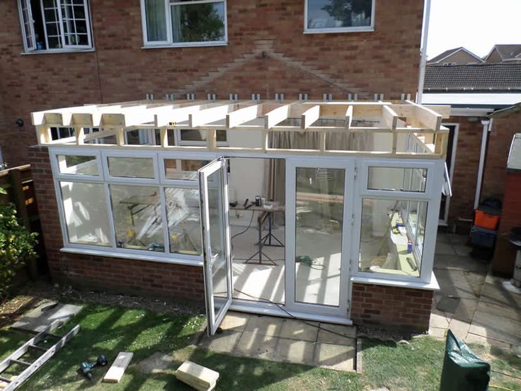 a house that is being built in the yard with windows on each side and doors open