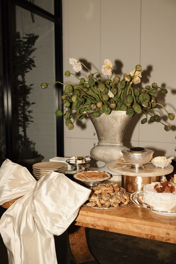 the table is covered with desserts and flowers in a vase on top of it