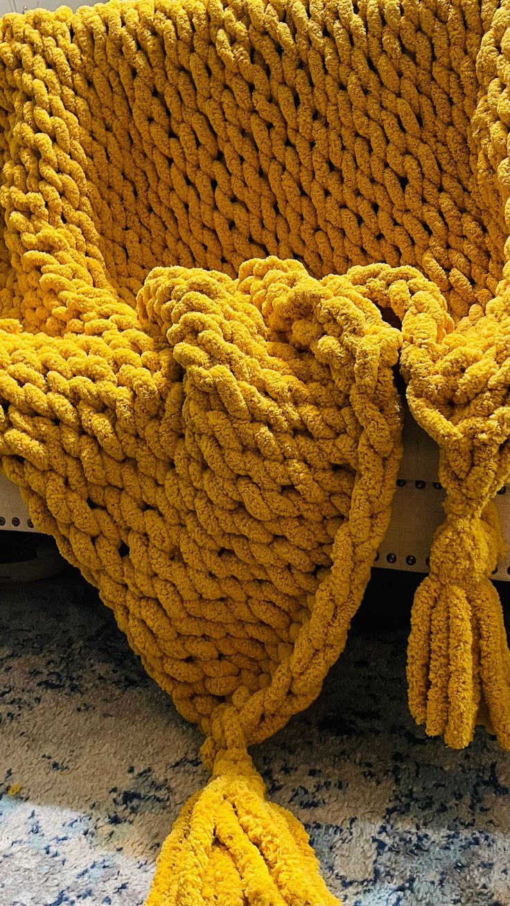 a yellow knitted chair with tassels on it