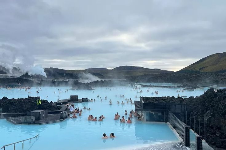 people are swimming in the blue lagoon on a cloudy day