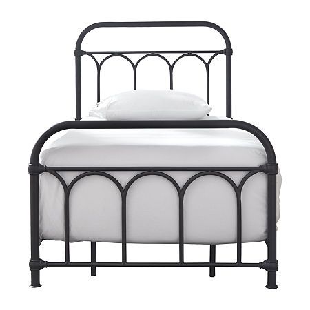 an iron bed frame with white sheets and pillows on the headboard, against a white background