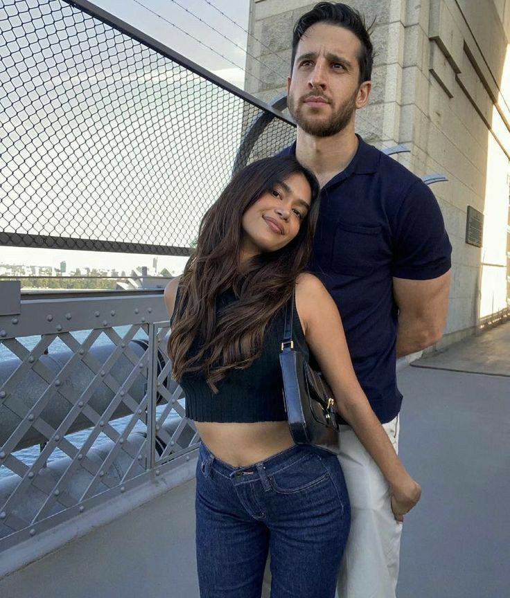 a man standing next to a woman on top of a bridge