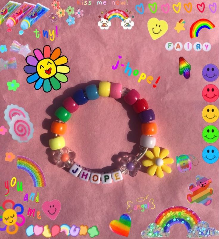 a bunch of colorful bracelets on top of a pink surface with smiley face stickers