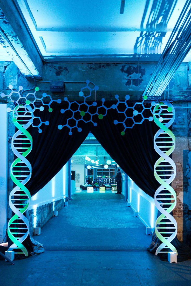 the entrance to a building decorated with black drapes and neon green ribbons, in front of a blue backdrop