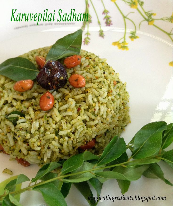 a white plate topped with rice covered in vegetables and sauces next to green leaves