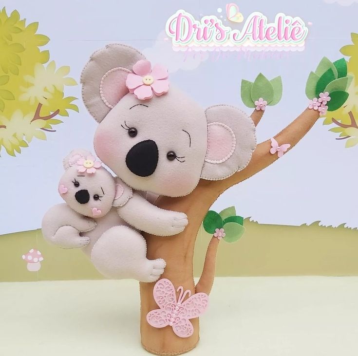 a stuffed koala bear and her baby are sitting on a tree branch with pink flowers