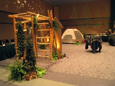 a room filled with tables and chairs covered in green tablecloths next to a wooden ladder