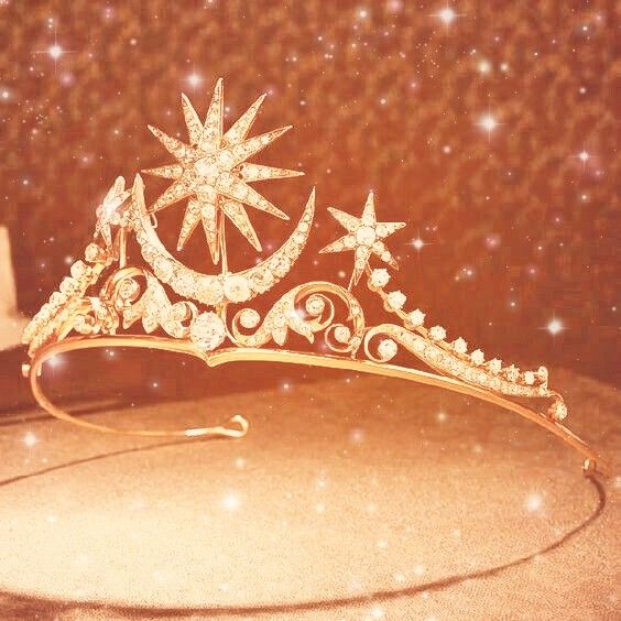 a gold tiara with stars and pearls on it's headband, sitting on a table