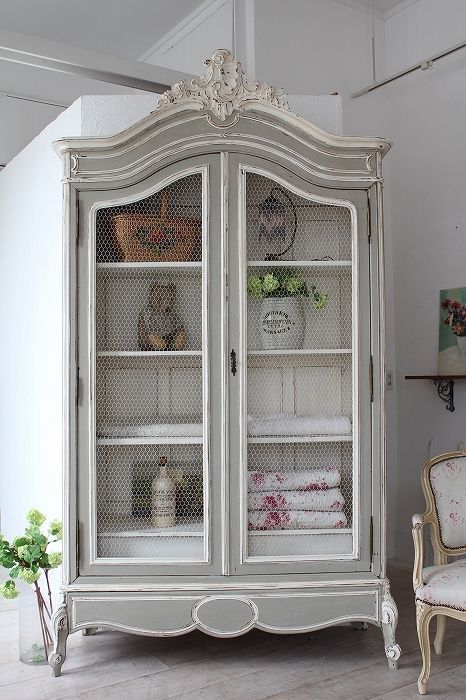 an old white china cabinet with glass doors and shelves in the middle of a room