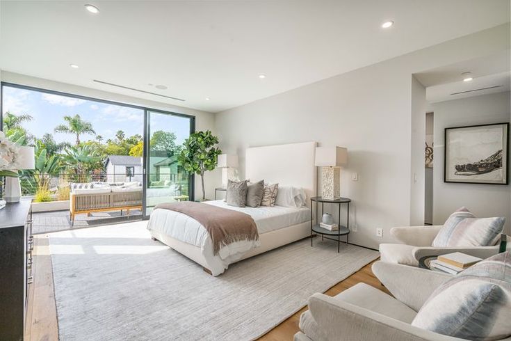 a bedroom with two beds, couches and large windows