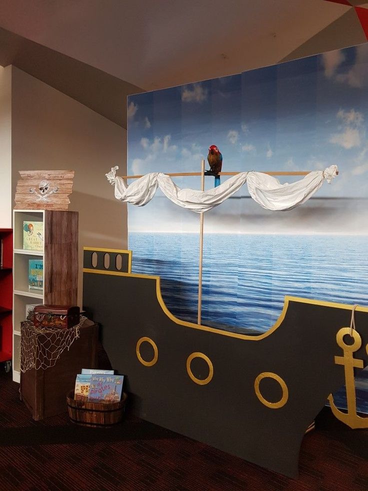 there is a pirate ship painted on the wall in this children's room with bookshelves