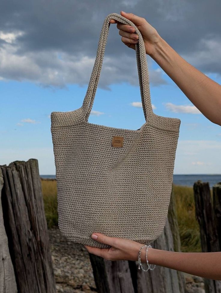 Elevate your everyday style with this chic and versatile handmade macrame bag. Crafted from durable polyester cord, this bag is perfect for carrying your essentials, whether you're heading to the beach, running errands, or simply going about your day. Key Features: Modern Design: The sleek and minimalist design makes this bag a stylish addition to any outfit. Durable Construction: Made from high-quality polyester cord, this bag is built to last. Versatile Use: Perfect for carrying your essentials on the beach, to the store, or for everyday use. Unique Gift: This handmade bag makes a thoughtful and one-of-a-kind gift for any occasion. Order yours today and experience the perfect blend of style and functionality. Crochet Bag With Wooden Handles, Bag With Wooden Handles, Casual Sling Bag, Boho Chic Bags, Beach Running, Handmade Crochet Bags, Grey Bag, Crochet Mini Dress, Macrame Bag