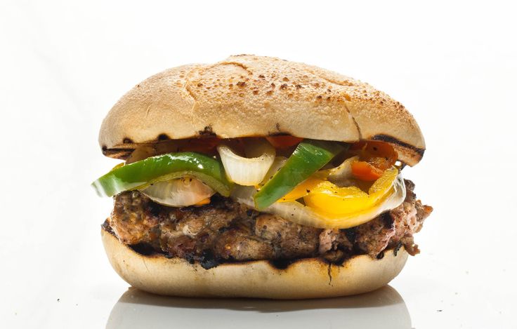 a hamburger with meat, peppers and onions on a white surface in front of a white background