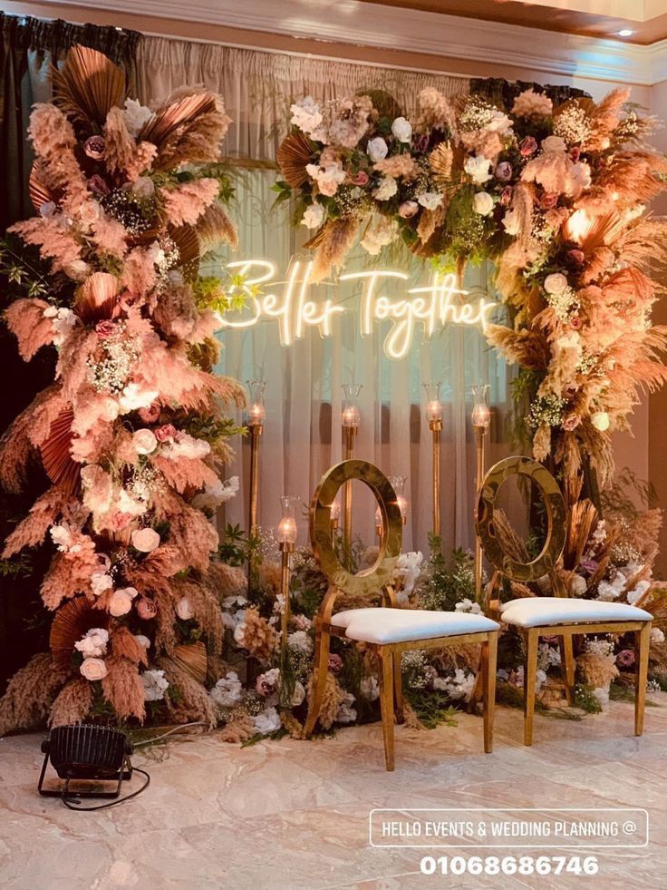 a couple of chairs sitting in front of a wall with flowers and candles on it