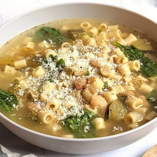 a bowl of pasta and spinach soup with parmesan sprinkles