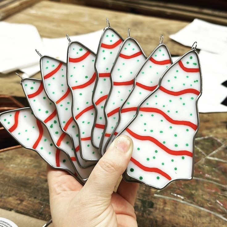 a hand holding a glass decoration with red and green stripes