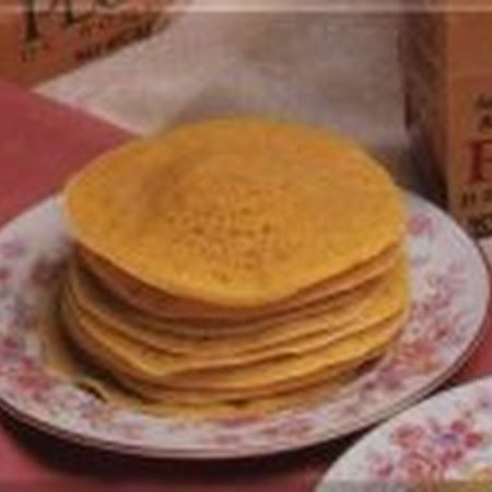 a stack of pancakes sitting on top of a plate next to a carton of milk