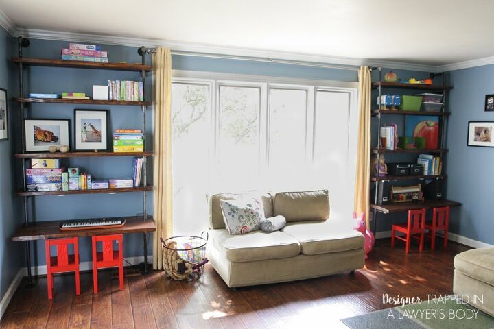 a living room filled with furniture and bookshelves next to a window covered in curtains