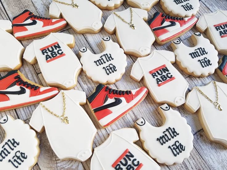 cookies decorated like shoes and t - shirts are arranged on a wooden table with gold chains