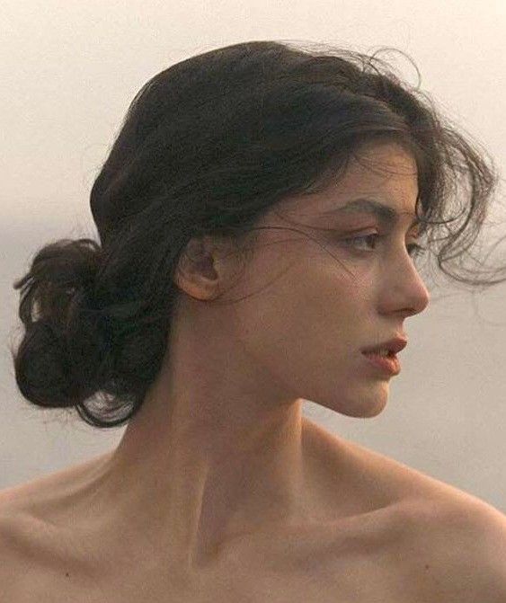 a close up of a woman with no shirt on and her hair blowing in the wind